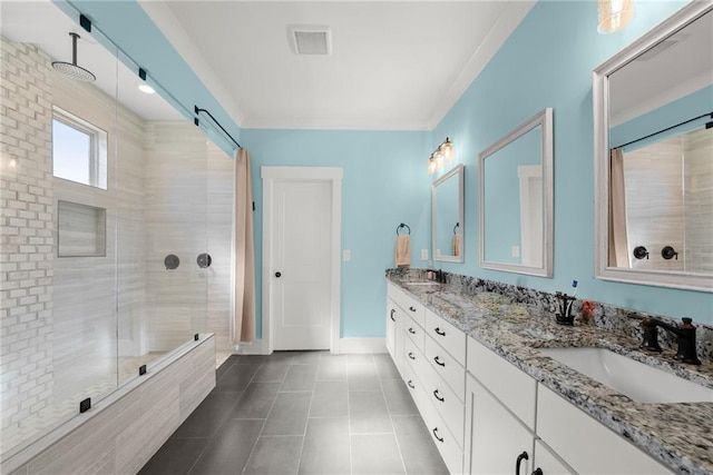 full bath featuring a sink, visible vents, baseboards, a tile shower, and double vanity