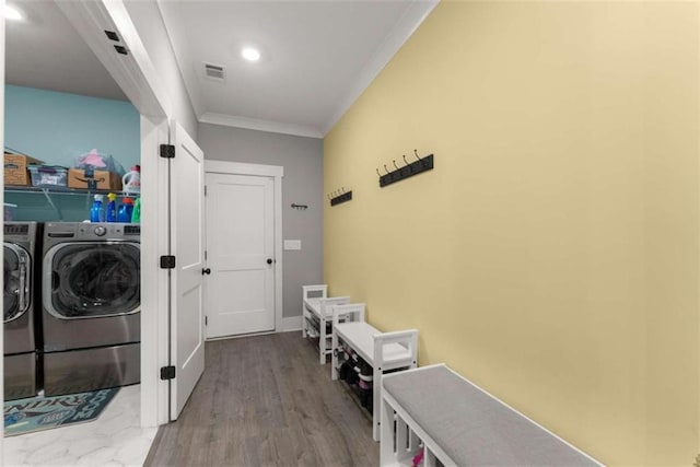 clothes washing area featuring laundry area, visible vents, wood finished floors, crown molding, and washing machine and dryer