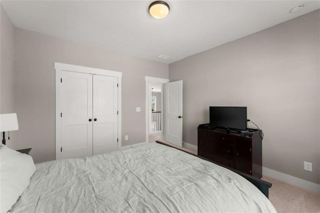 carpeted bedroom featuring a closet and baseboards