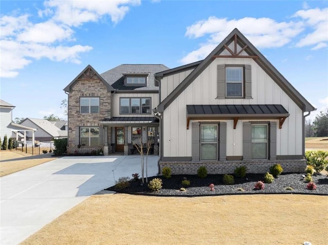 view of front facade featuring metal roof, brick siding, driveway, board and batten siding, and a standing seam roof