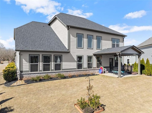 back of house featuring a yard, brick siding, roof with shingles, and a patio area