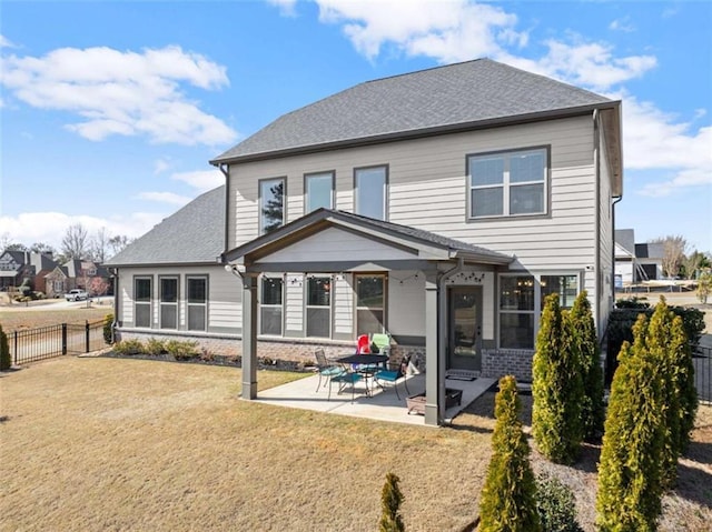 back of house with a patio, a fenced backyard, roof with shingles, a yard, and brick siding