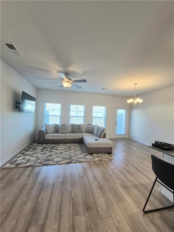 living room featuring ceiling fan with notable chandelier and light hardwood / wood-style floors