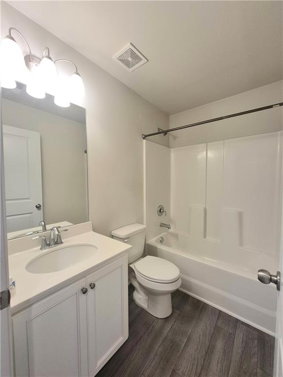 full bathroom featuring shower / bathing tub combination, vanity, hardwood / wood-style flooring, and toilet