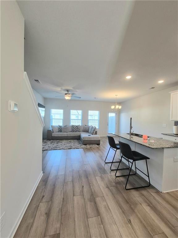 interior space featuring ceiling fan with notable chandelier, light wood-type flooring, and sink