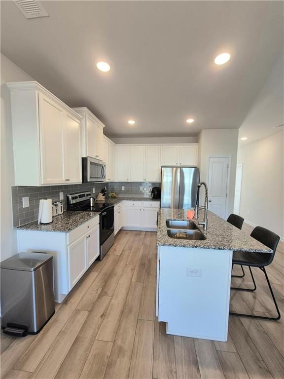 kitchen featuring sink, stainless steel appliances, tasteful backsplash, light hardwood / wood-style flooring, and white cabinets