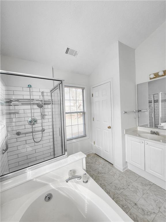 bathroom with plus walk in shower, lofted ceiling, vanity, and a textured ceiling