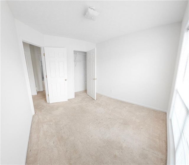 unfurnished bedroom with multiple windows, light colored carpet, and a closet