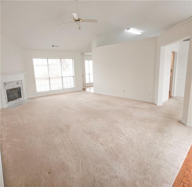 unfurnished living room with light carpet, crown molding, a premium fireplace, and ceiling fan