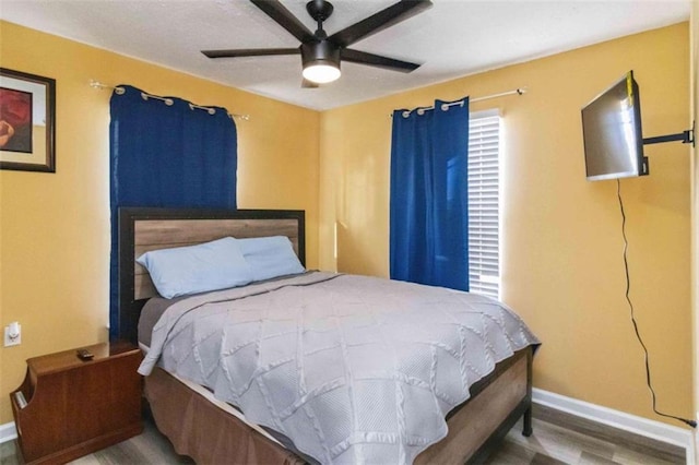 bedroom with ceiling fan, baseboards, and wood finished floors