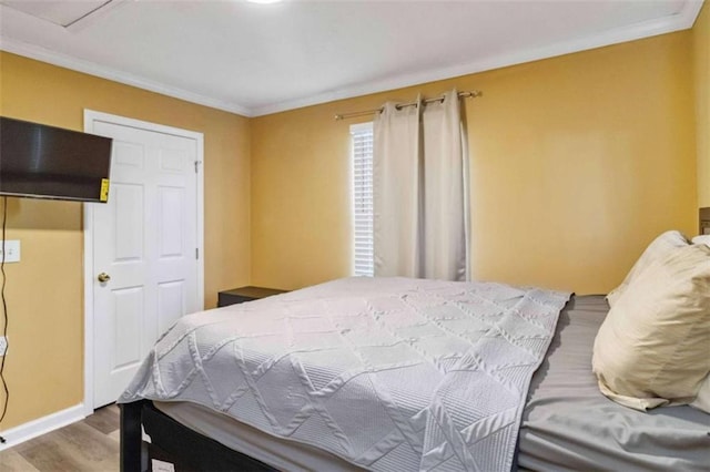 bedroom with crown molding, wood finished floors, and baseboards