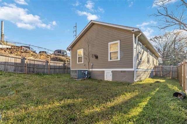 rear view of property with central air condition unit, a yard, and a fenced backyard