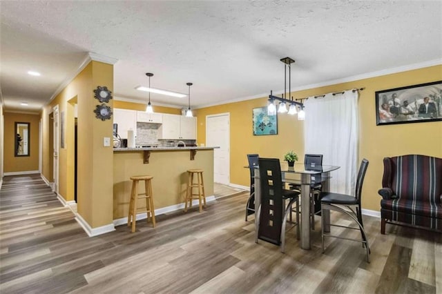 dining room with crown molding, dark wood-style floors, baseboards, and a textured ceiling