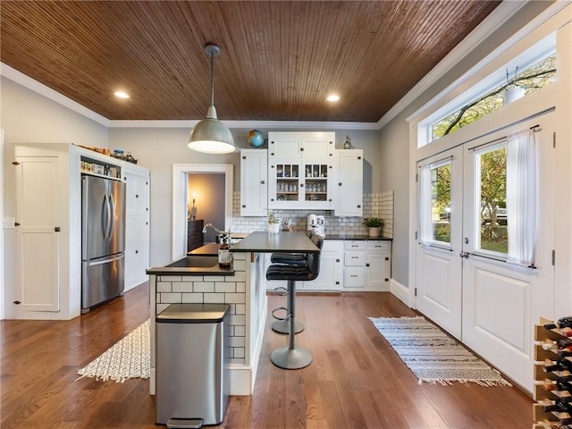 kitchen featuring white cabinets, pendant lighting, dark wood-type flooring, and stainless steel refrigerator