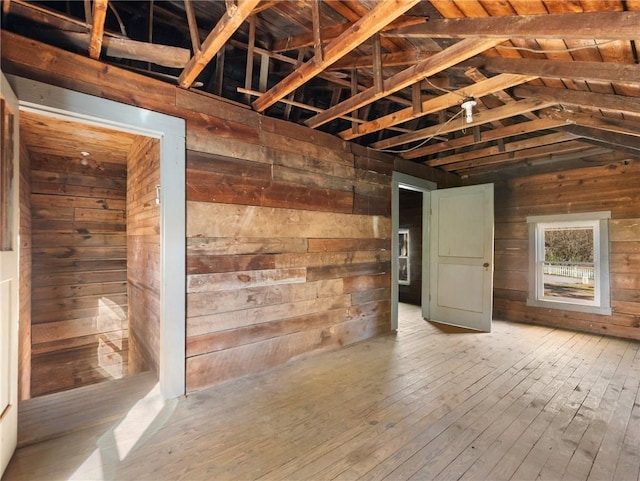 unfurnished room featuring wood-type flooring, vaulted ceiling, and wooden walls