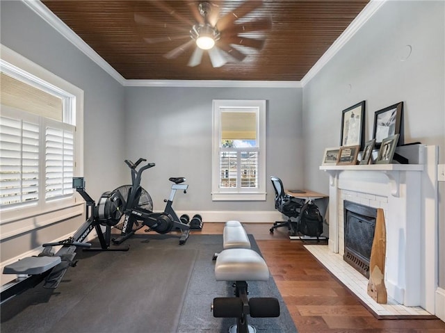 workout room featuring ornamental molding, dark hardwood / wood-style floors, a brick fireplace, and a healthy amount of sunlight