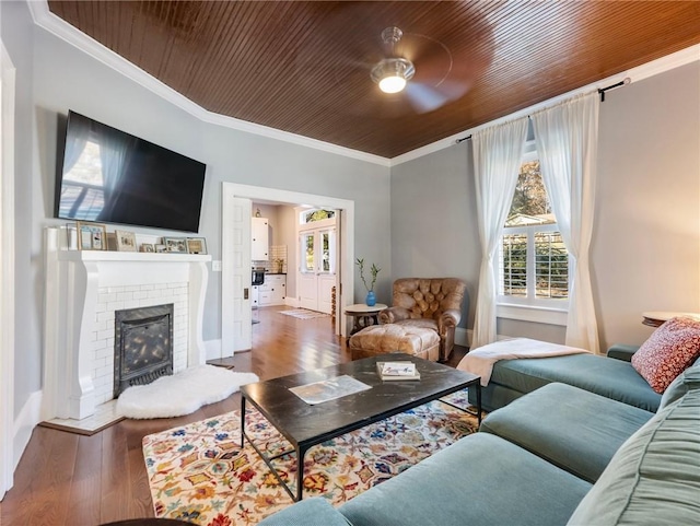 living room featuring a brick fireplace, wood ceiling, ceiling fan, crown molding, and wood-type flooring