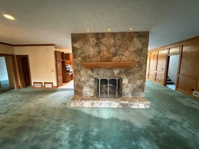 unfurnished living room featuring ornamental molding, a stone fireplace, and carpet flooring