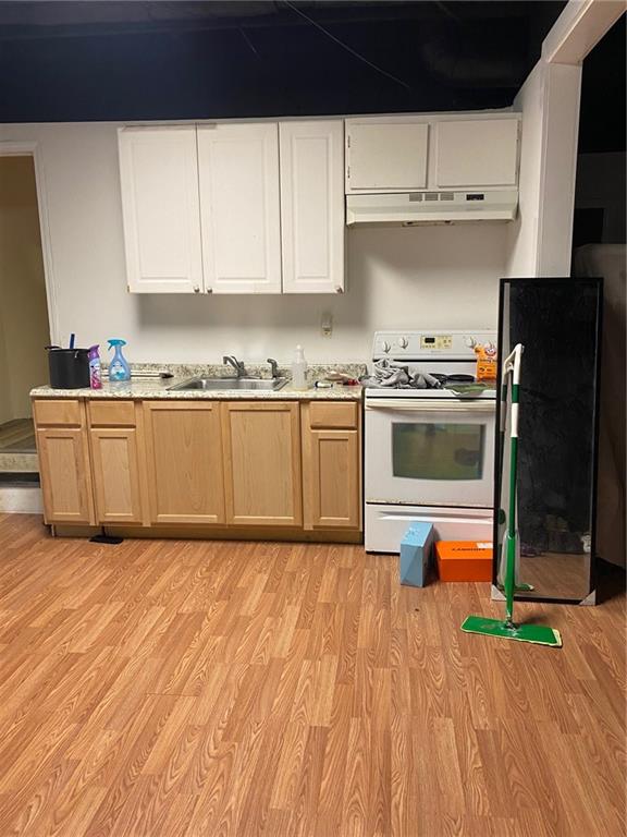 kitchen featuring white stove, white cabinetry, and light hardwood / wood-style flooring