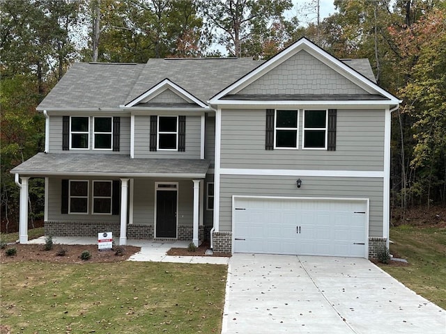 craftsman inspired home with brick siding, a porch, an attached garage, driveway, and a front lawn