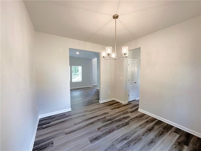 unfurnished dining area with an inviting chandelier, baseboards, and dark wood-style flooring