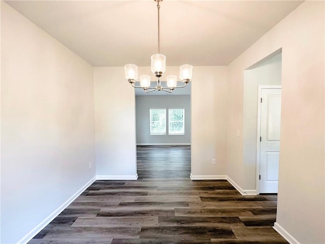 unfurnished dining area with a chandelier, dark wood-style flooring, and baseboards