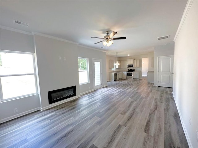 unfurnished living room featuring visible vents, crown molding, and baseboards