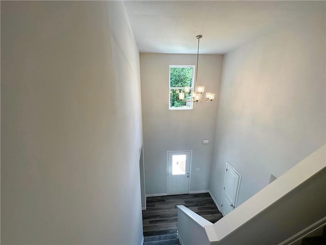 interior space featuring baseboards, a high ceiling, dark wood finished floors, and an inviting chandelier