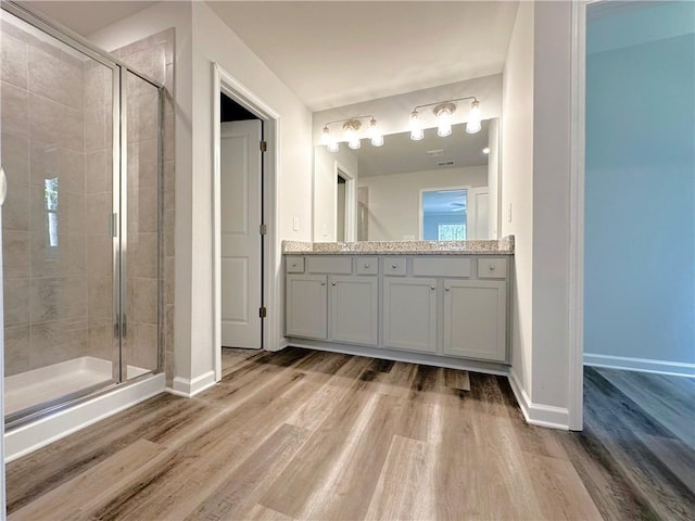 full bath with wood finished floors, a shower stall, vanity, and baseboards