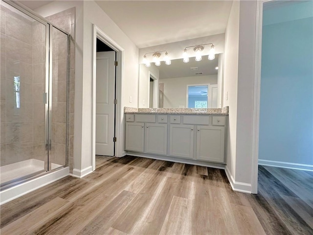 bathroom with vanity, a shower stall, baseboards, and wood finished floors