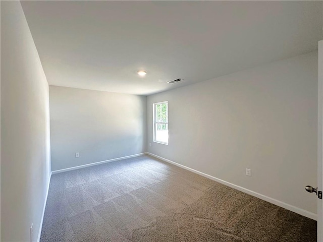 carpeted spare room featuring visible vents and baseboards