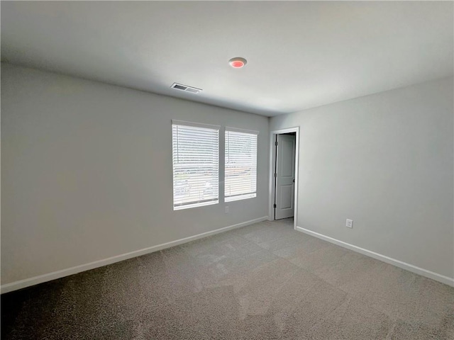 empty room featuring light colored carpet, visible vents, and baseboards