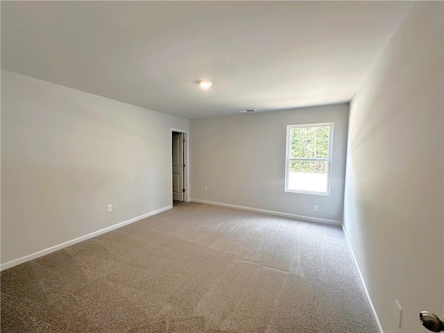 spare room with light carpet, visible vents, and baseboards