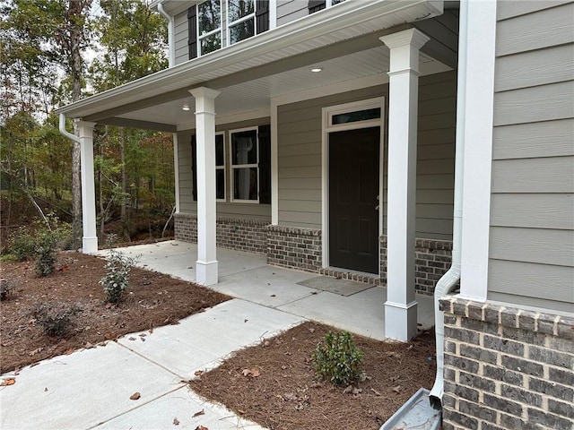 entrance to property featuring brick siding and a porch