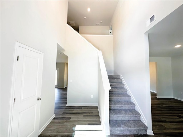 stairs with wood finished floors, visible vents, and baseboards