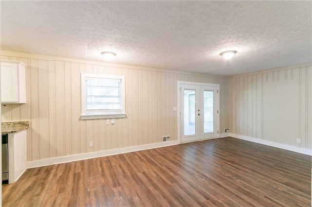 empty room featuring dark wood-type flooring, a textured ceiling, and french doors