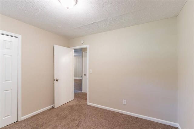 unfurnished bedroom featuring a textured ceiling, carpet flooring, and a closet