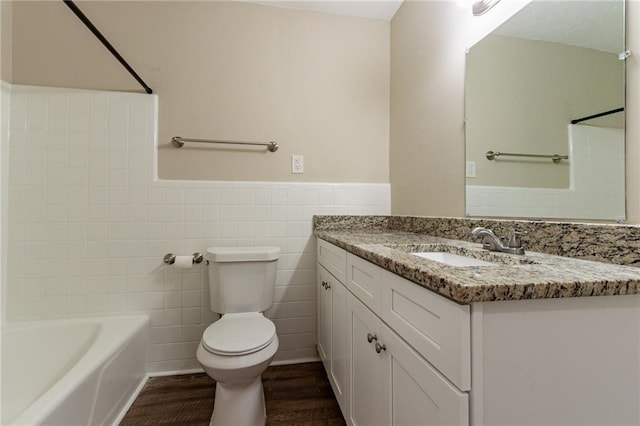 full bathroom with shower / bathing tub combination, hardwood / wood-style floors, tile walls, toilet, and vanity