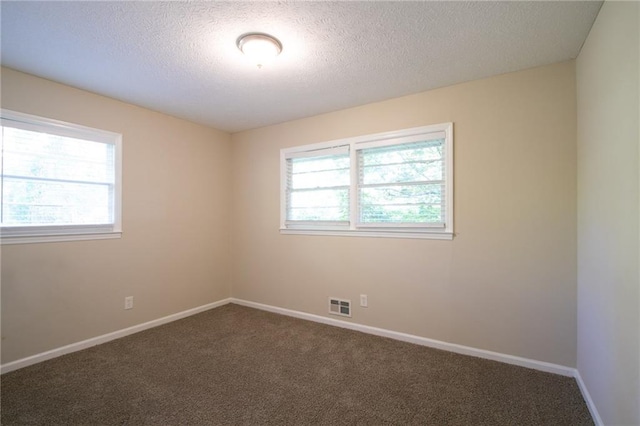 carpeted empty room with a textured ceiling