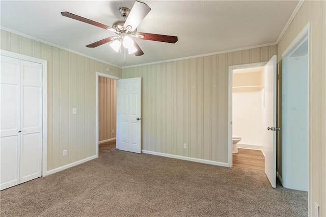 unfurnished bedroom featuring light carpet, ornamental molding, ensuite bath, and ceiling fan