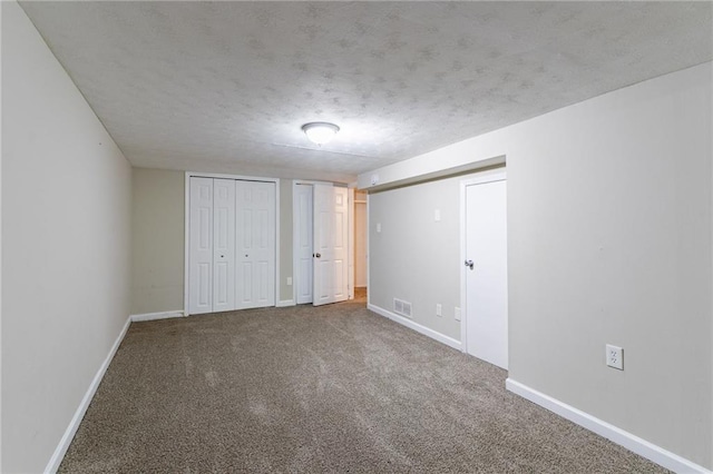 unfurnished bedroom with carpet floors, multiple closets, and a textured ceiling