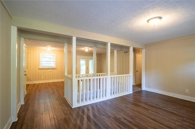 spare room with french doors, a textured ceiling, and dark hardwood / wood-style flooring