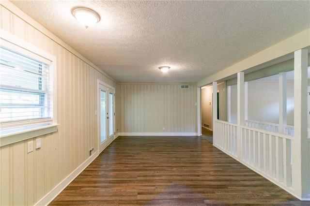 unfurnished room with a textured ceiling and dark wood-type flooring