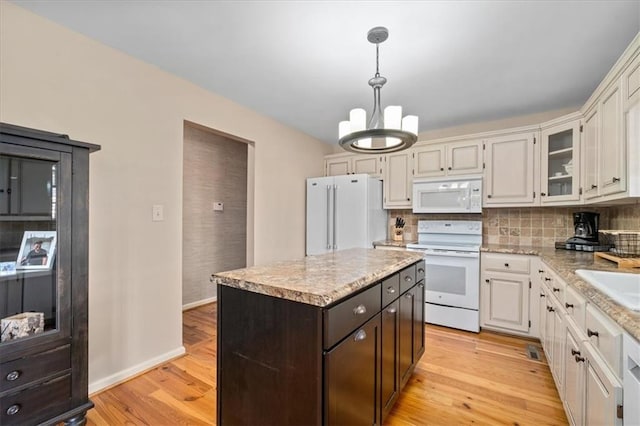 kitchen featuring decorative backsplash, white appliances, a notable chandelier, and light wood finished floors