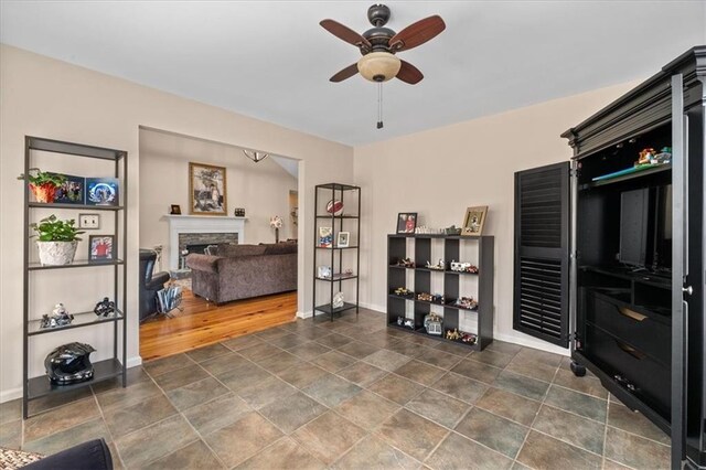 interior space featuring baseboards, a stone fireplace, and a ceiling fan