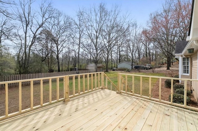 wooden terrace featuring a storage shed, an outbuilding, a yard, and fence