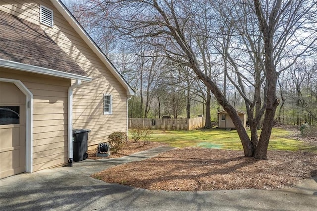 view of yard with an outbuilding, driveway, and fence