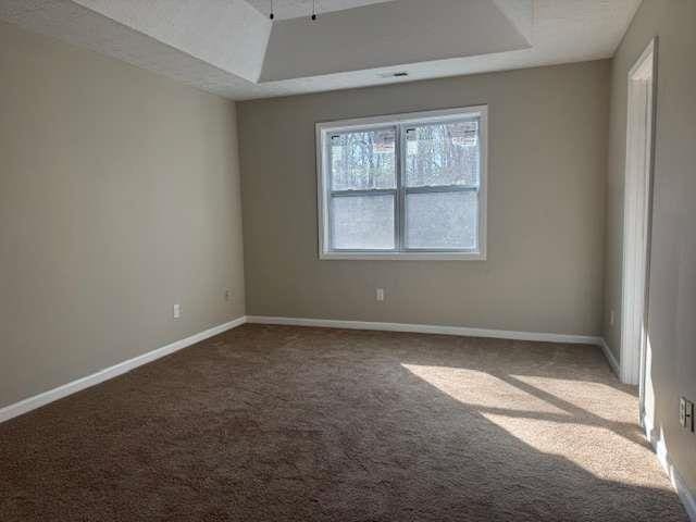 carpeted empty room with baseboards and a tray ceiling