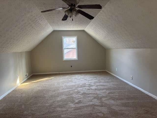 bonus room featuring lofted ceiling, baseboards, a textured ceiling, and carpet flooring