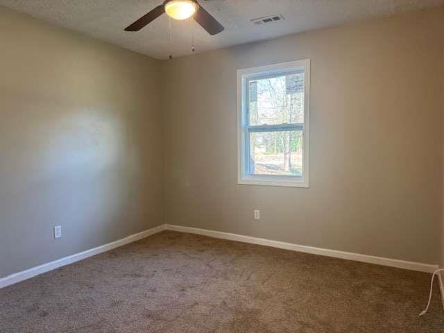 empty room with ceiling fan, carpet flooring, visible vents, and baseboards